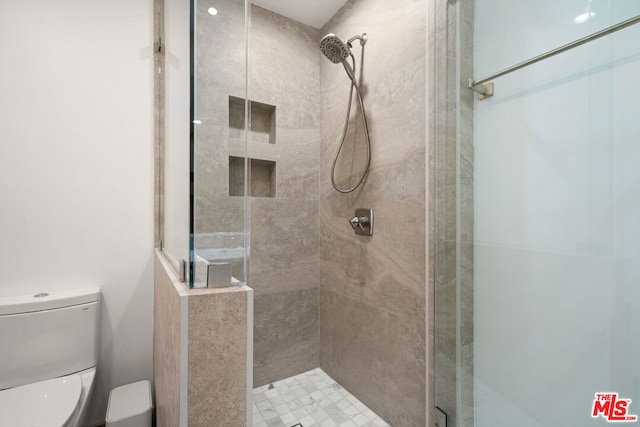 bathroom with toilet and a tile shower