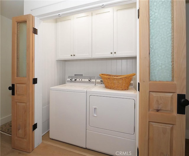 clothes washing area with separate washer and dryer and cabinets