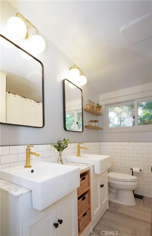 bathroom featuring toilet, vanity, lofted ceiling, and tile walls