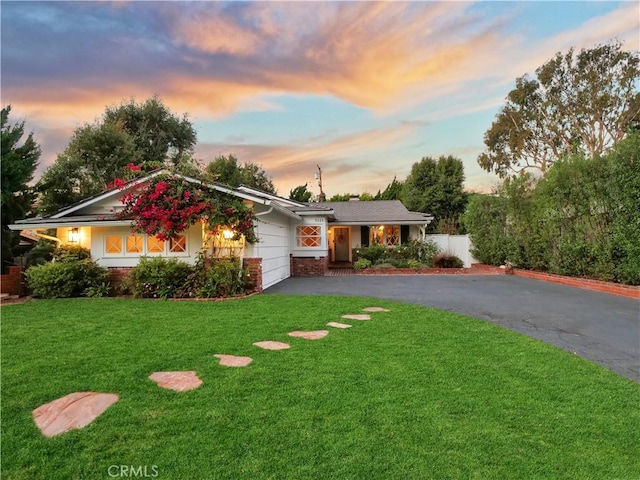 ranch-style house featuring a garage and a yard