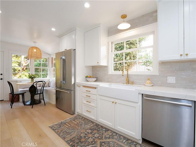 kitchen with decorative light fixtures, sink, white cabinets, and appliances with stainless steel finishes