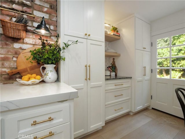 kitchen featuring light stone countertops, white cabinets, and light wood-type flooring