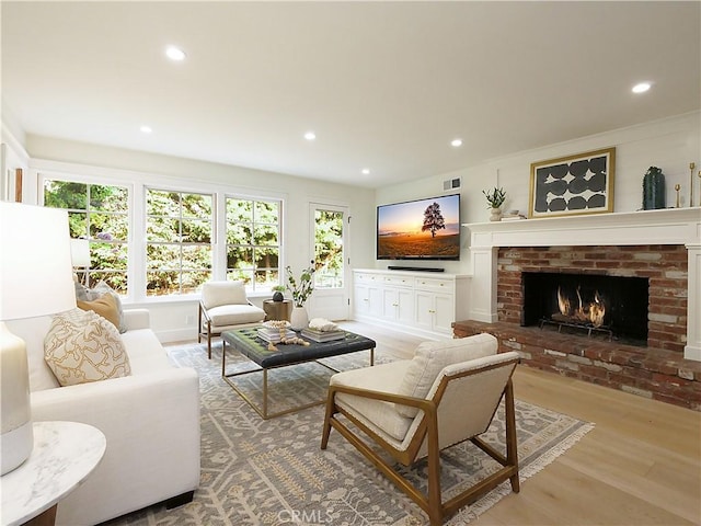 living room featuring a brick fireplace and light hardwood / wood-style flooring