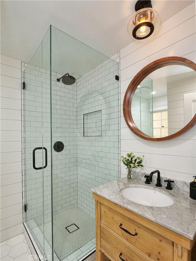 bathroom featuring vanity, a shower with shower door, wood walls, and tile patterned floors