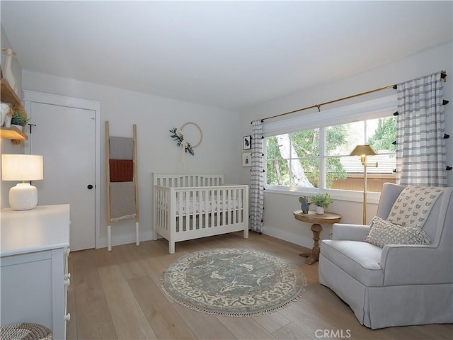 bedroom with light wood-type flooring and a crib