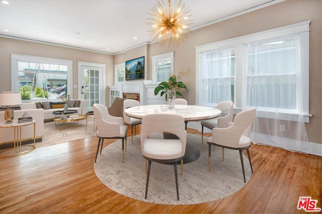 dining space with hardwood / wood-style flooring, ornamental molding, and an inviting chandelier