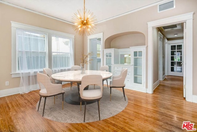 dining area with light hardwood / wood-style flooring, crown molding, and a chandelier