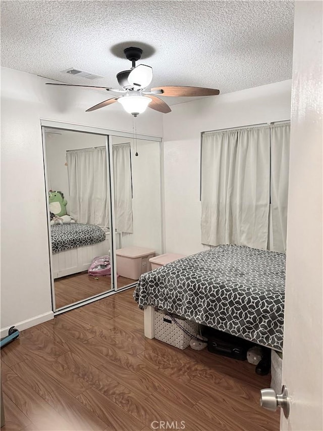 bedroom with hardwood / wood-style floors, a textured ceiling, a closet, and ceiling fan