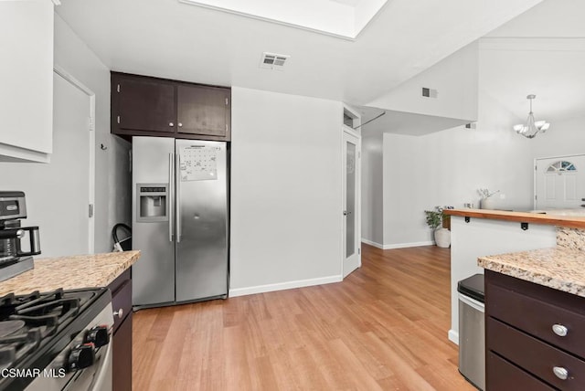 kitchen featuring appliances with stainless steel finishes, dark brown cabinets, a notable chandelier, and light hardwood / wood-style floors