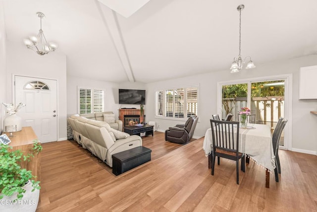 living room featuring lofted ceiling with beams, a chandelier, and light hardwood / wood-style flooring