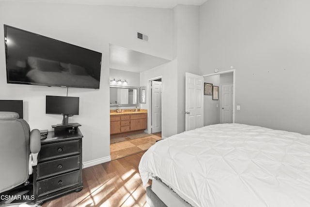 bedroom with lofted ceiling, hardwood / wood-style floors, and ensuite bath