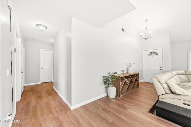 hallway featuring lofted ceiling, a notable chandelier, and light hardwood / wood-style floors