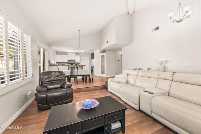 living room with a notable chandelier, hardwood / wood-style flooring, and high vaulted ceiling