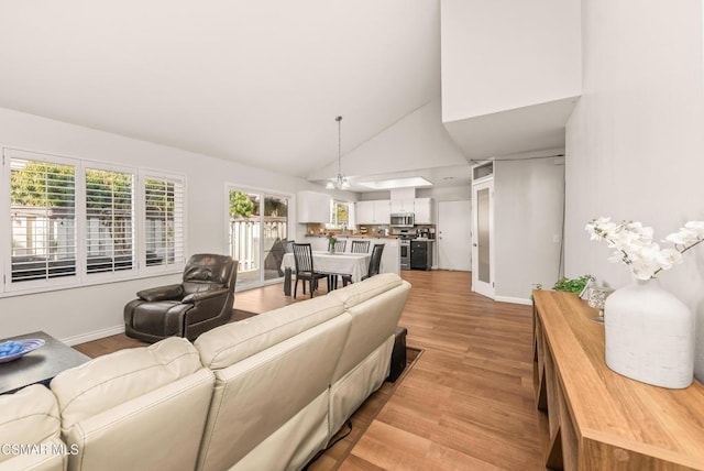 living room featuring high vaulted ceiling and light wood-type flooring