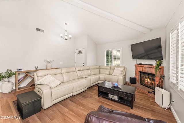 living room with a chandelier, hardwood / wood-style floors, a brick fireplace, and vaulted ceiling with beams