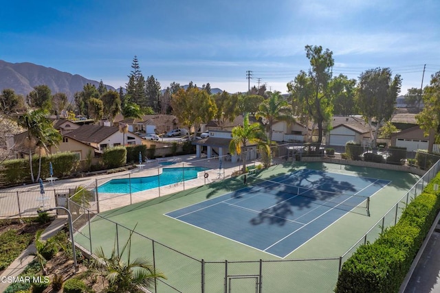 view of tennis court featuring a fenced in pool and a mountain view