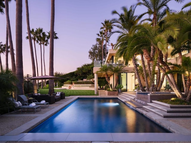 pool at dusk featuring a patio and outdoor lounge area