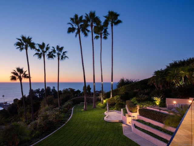 yard at dusk featuring a water view