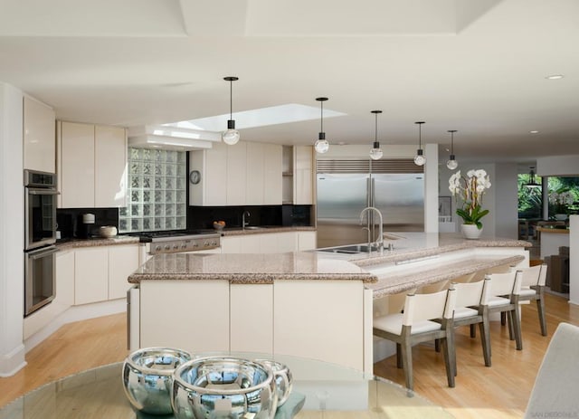 kitchen featuring white cabinets, stainless steel appliances, pendant lighting, and a spacious island