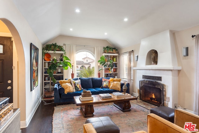 living room with a fireplace, dark wood-type flooring, and vaulted ceiling