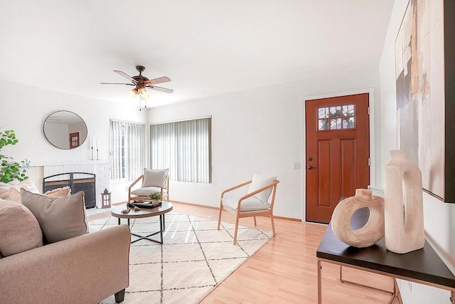 living room with ceiling fan, a fireplace, and light hardwood / wood-style flooring