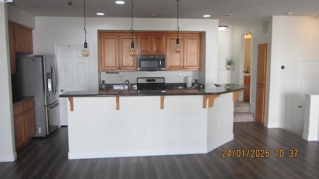 kitchen with pendant lighting, stainless steel appliances, dark hardwood / wood-style floors, and a kitchen bar