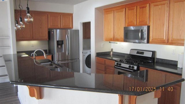 kitchen featuring stainless steel appliances, a kitchen breakfast bar, washer / dryer, and sink