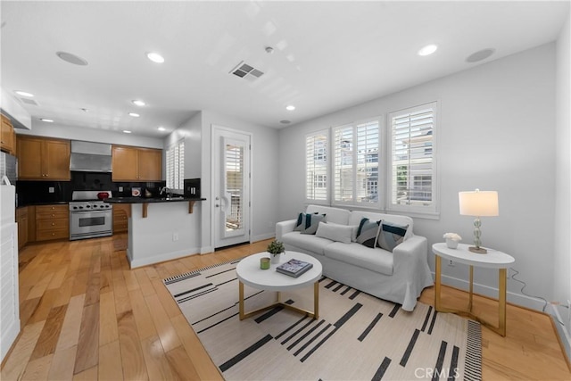 living room with light wood finished floors, visible vents, and recessed lighting