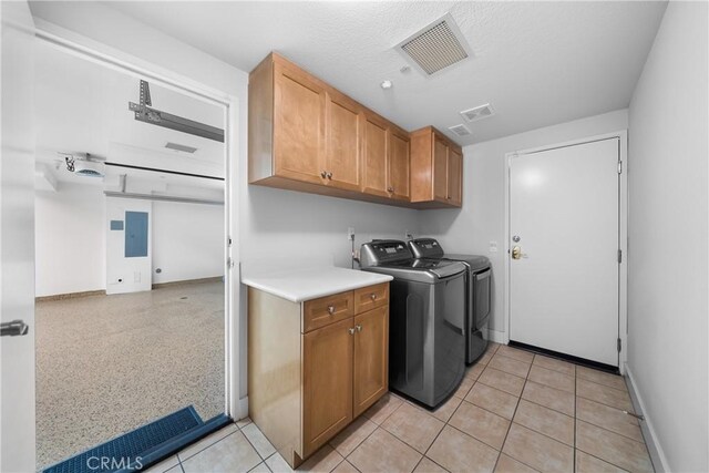 laundry room featuring electric panel, separate washer and dryer, cabinets, and light tile patterned floors