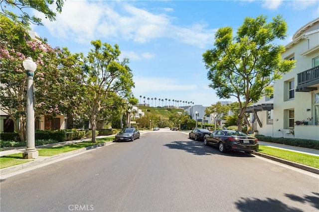 view of road with sidewalks, street lighting, a residential view, and curbs