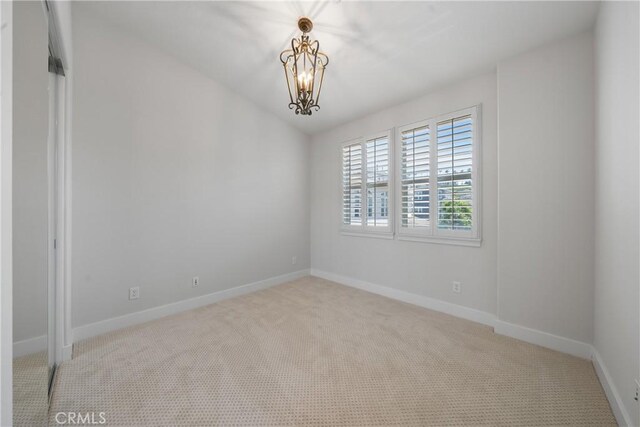 carpeted empty room with a chandelier