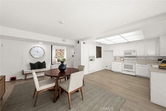 dining space featuring sink, light hardwood / wood-style flooring, and a textured ceiling