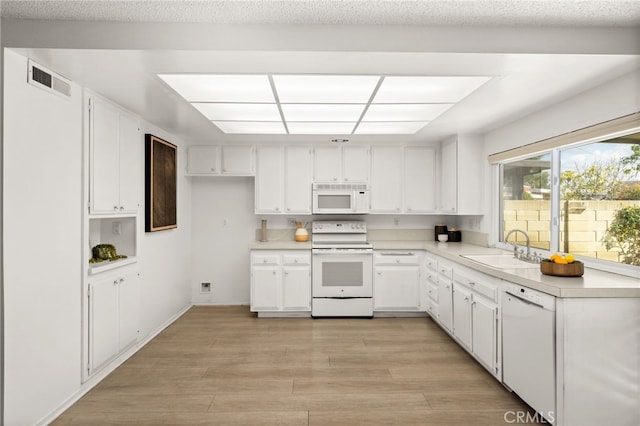 kitchen with white cabinets, white appliances, light hardwood / wood-style flooring, and sink