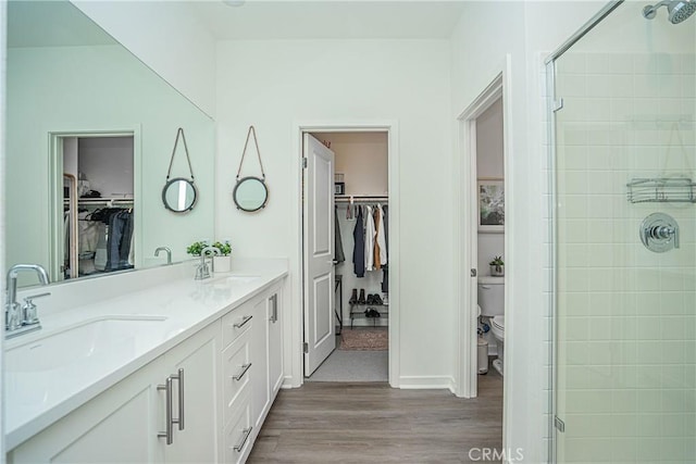 bathroom with vanity, toilet, a shower with door, and wood-type flooring