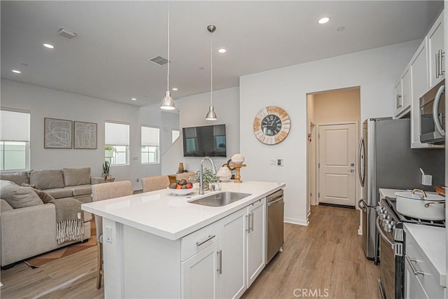 kitchen with sink, an island with sink, white cabinetry, and stainless steel appliances