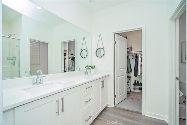 bathroom featuring hardwood / wood-style flooring, a shower with shower door, vanity, and toilet