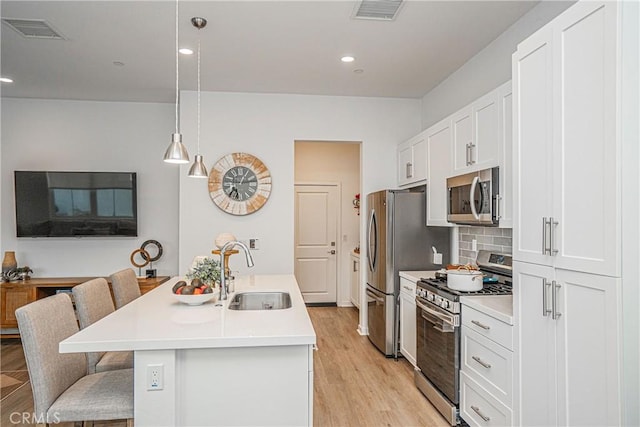 kitchen with sink, white cabinets, appliances with stainless steel finishes, and pendant lighting