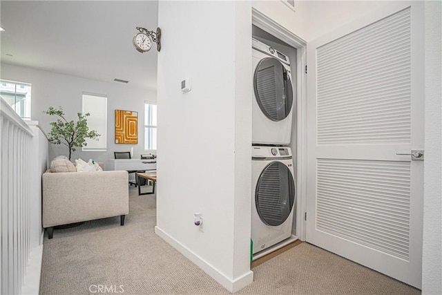 laundry room featuring stacked washer / dryer and light carpet