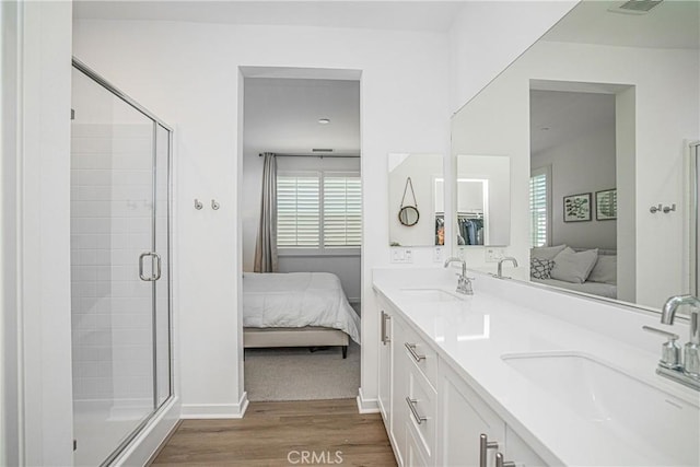 bathroom featuring hardwood / wood-style floors, a shower with door, and vanity