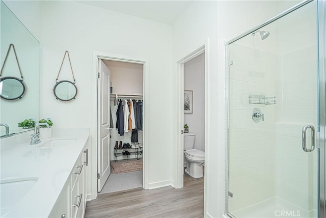 bathroom with vanity, toilet, a shower with door, and wood-type flooring