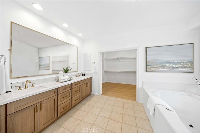 full bathroom with double vanity, a sink, a walk in closet, and tile patterned floors