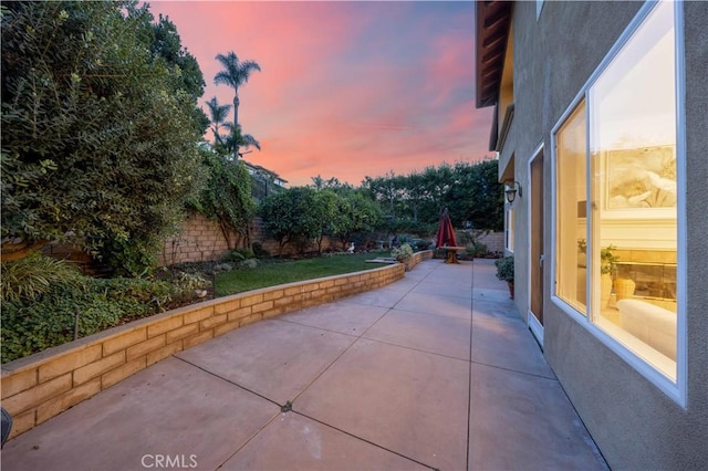 patio terrace at dusk featuring a fenced backyard