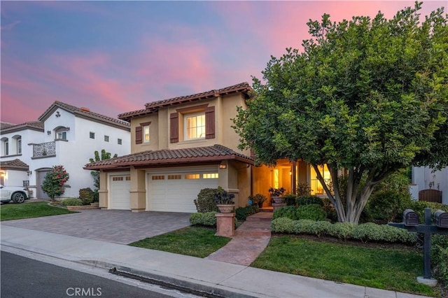 view of front of home with decorative driveway, a tiled roof, an attached garage, and stucco siding