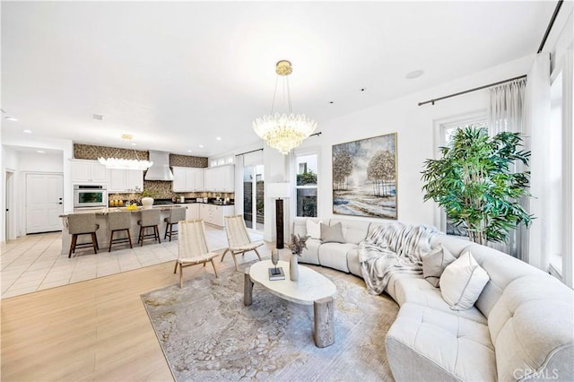 living area with recessed lighting, plenty of natural light, an inviting chandelier, and light wood-style floors