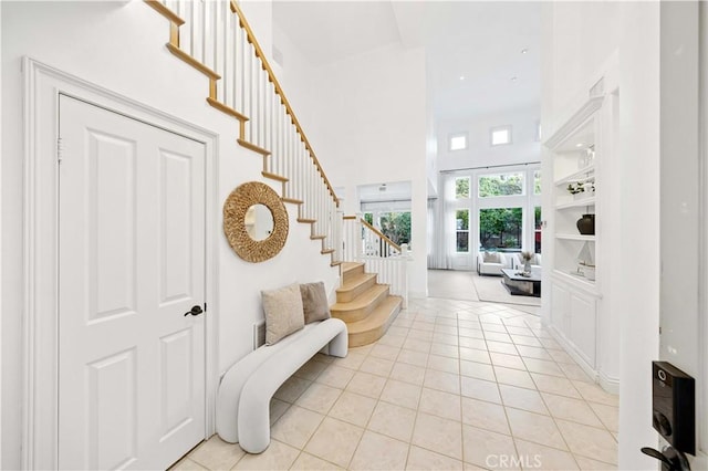 entrance foyer with stairs, a high ceiling, and light tile patterned floors