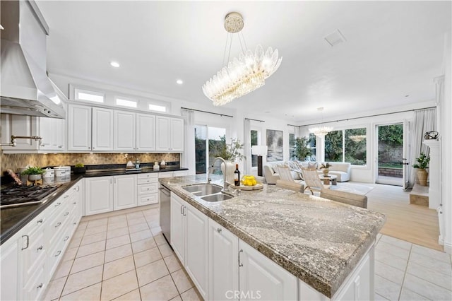 kitchen with a center island with sink, island range hood, an inviting chandelier, white cabinetry, and a sink