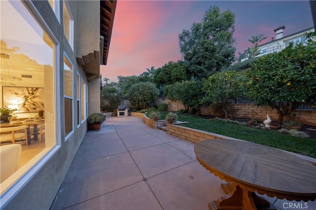 patio terrace at dusk featuring a fenced backyard and visible vents