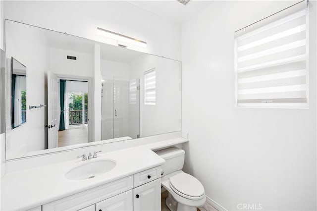 bathroom with a stall shower, visible vents, baseboards, toilet, and vanity