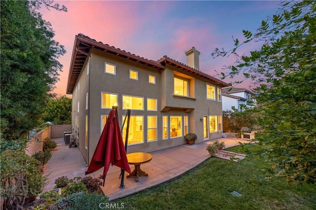 rear view of house with a patio area, a chimney, and stucco siding