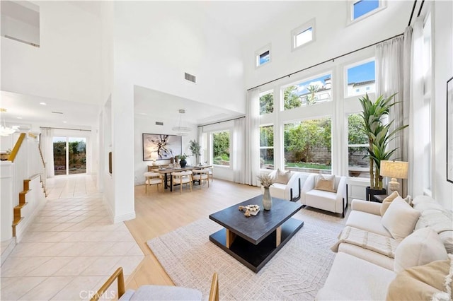 living room featuring light tile patterned floors, a high ceiling, and visible vents